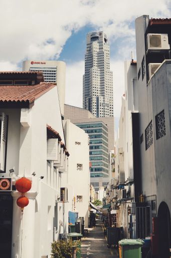 View of a narrow alley in Singapore's Chinatown, skyscrapers in background