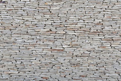 Close up of a stone wall made of small flat stones. Abstract and geometry concept.