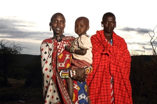 A shallow focus shot of an African couple with their baby looking at the camera