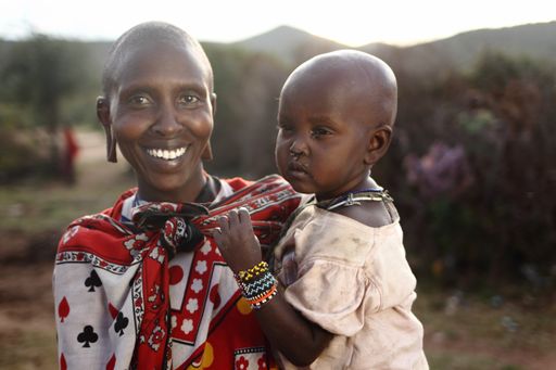 A shallow focus shot of an African mother with its baby while smiling at the camera