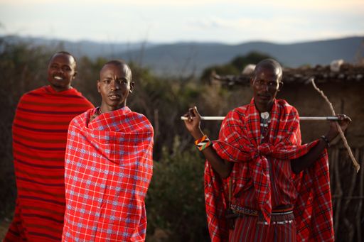 A shallow focus shot of three African males with blankets wrapped around them