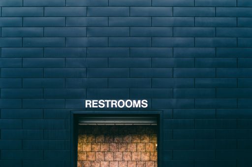 A closeup of a blue brick wall with "restrooms" door in the middle
