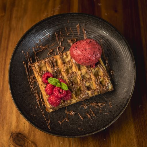 A delicious tasty dessert made with waffles, refreshing ice-cream, and fresh raspberries