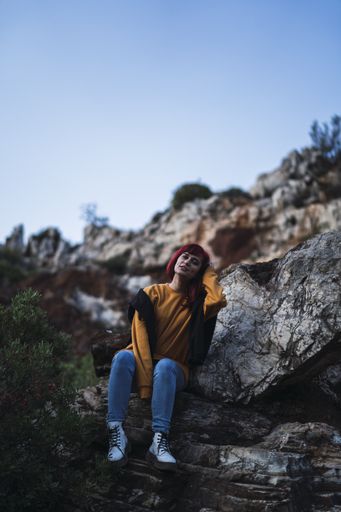 A low angle shot of a beautiful woman sitting on stones