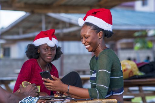 A selective focus shot of beautiful black women wearing Christmas hats looking at a cellphone