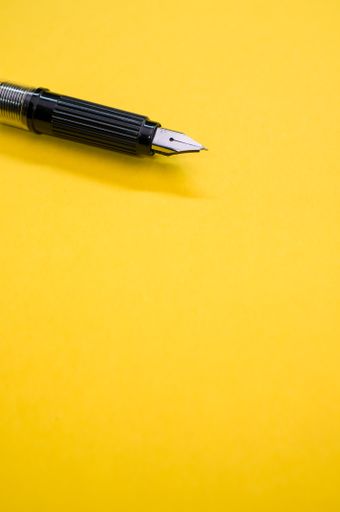 A closeup of a fountain pen on the yellow surface - space for text