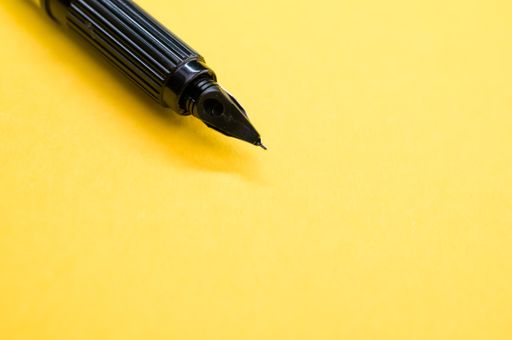 A closeup of a fountain pen on the yellow surface - space for text