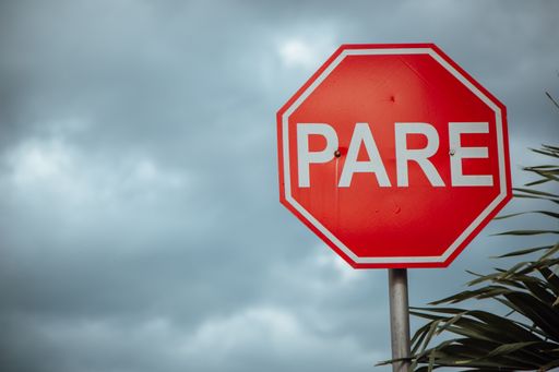 A stop sign in Spanish pare sign under a cloudy sky