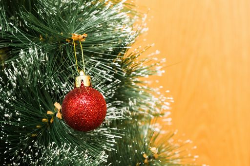A closeup of a red ornament on a Christmas tree under the lights