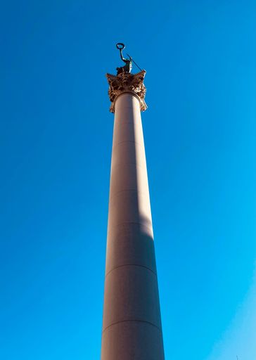 A vertical low angle of the Dewey Monument on a high tower against a blue sky in San Francisco, California