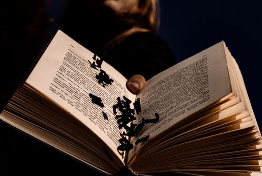A person holding an open book with letters falling out