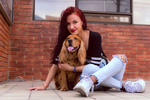 A closeup of an attractive Hispanic female posing with her cocker spaniel dog