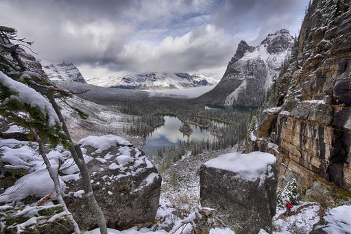 A beautiful scenery of a frozen lake in the middle of mountains covered in snow touching the sky