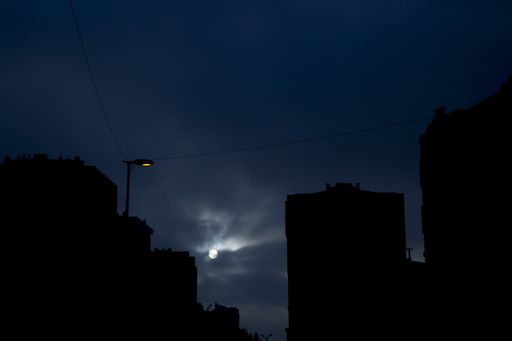 The full moon covered in clouds above residential buildings at night - great for wallpapers