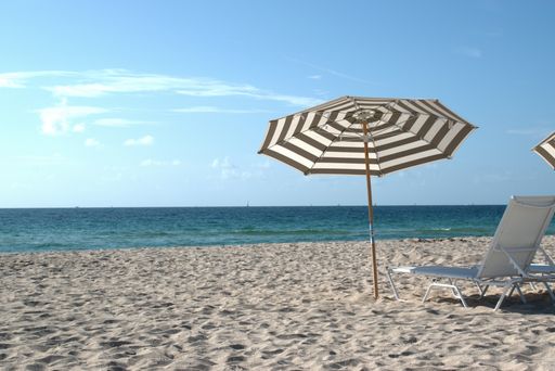 A closeup shot of a sun lounger and an umbrella on the beach on a sunny day