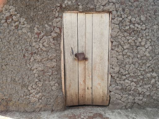 A closeup of an old wooden door in a mud house