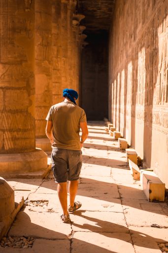 A vertical shot of a Caucasian man with a scarf on his head in The Temple of Horus at Edfu, Egypt