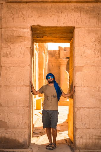 A young male wearing a blue Turban and leaning on the walls of The Temple of Horus at Edfu, Egypt