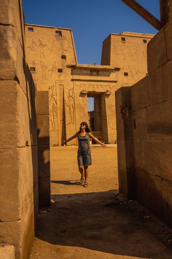 A vertical shot of a Caucasian woman in The Temple of Horus at Edfu, Egypt