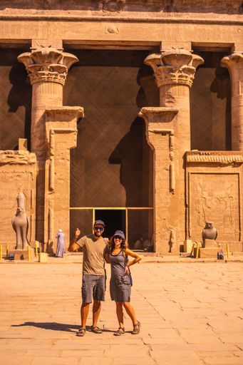 A vertical shot of a couple posing at The Temple of Horus at Edfu in Egypt