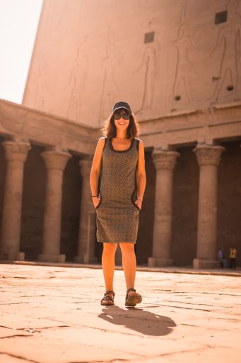 A vertical shot of a young female wearing a dress and walking around The Temple of Horus at Edfu, Egypt