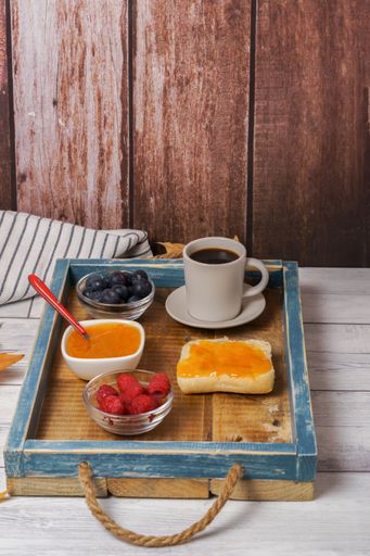 healthy breakfast on a wooden tray, homemade jam, red fruits and coffee with a dark wood background