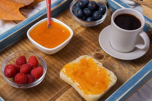 healthy breakfast on a wooden tray, homemade jam, red fruits and coffee with a dark wood background