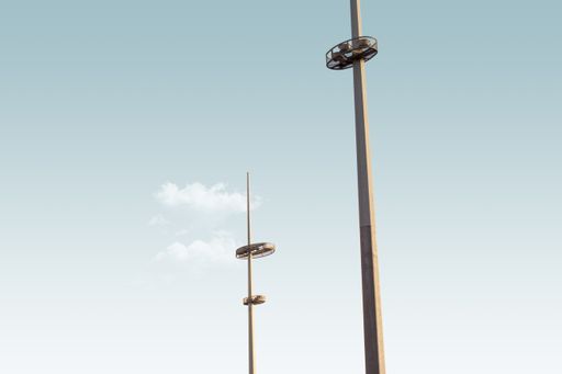 A low angle shot of two lamp post towers under the blue sky