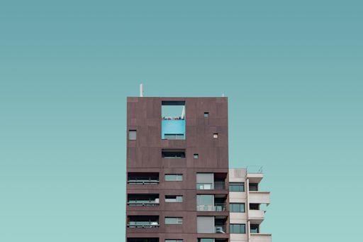 A vertical shot of a brown and white high rise building under the clear blue sky