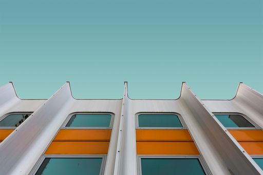 A low angle shot of a white and yellow modern building under the blue sky