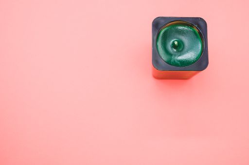 A top view of a decorative green candle on pink background with a copy space