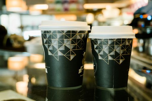 A closeup shot of plastic coffee cups in a coffee shop with a bokeh background