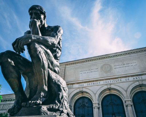 The Detroit Institute of Arts under a cloudy sky with the statue of The Thinker in front of it
