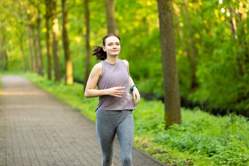 A young woman running in a forest and making fitness workout