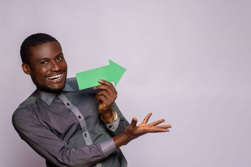 excited african man holding and arrow pointing sideways