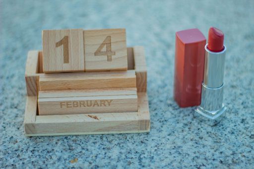 Wooden calendar with Valentine's Day placed on it with a woman's lipstick on the side to prepare for a date with her love.
