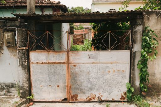 A closeup of an old rusty gate of a modest house