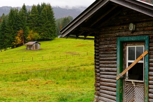The two wooden cabins on a bright green meadow