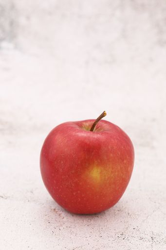A closeup of a fresh red apple on a white table