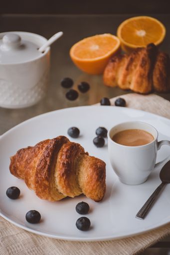A perfect morning breakfast - freshly baked croissants, a cup of coffee, orange and blueberries