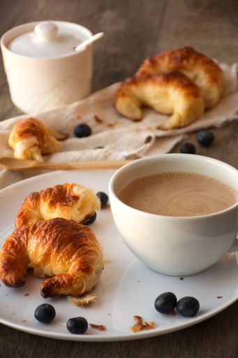 A perfect morning breakfast - freshly baked croissants, a cup of coffee, orange and blueberries