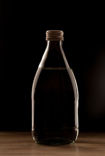 A transparent glass bottle filled with water on a dark background