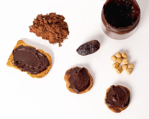 An overhead shot of cookies with chocolate spread wit a cacao bean and chocolate powder