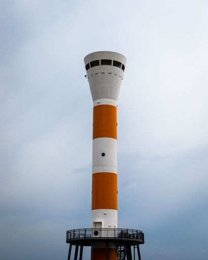 A vertical shot of a lighthouse with the background of sky