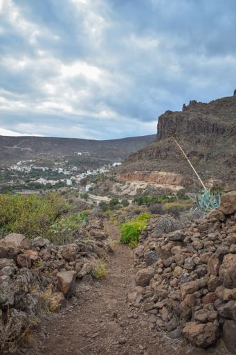 A vertical shot of hills covered in rocks and soil under a cloudy sky in the countryside