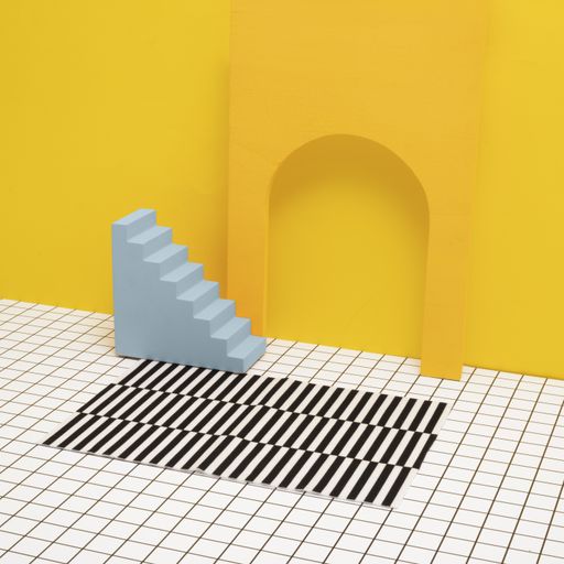 A miniature yellow room. The floor is checkered on black and white. There's a stripped carpet and a blue solid staircase that goes nowhere.