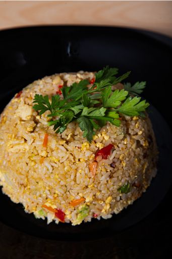 A vertical shot of delicious sauteed rice with chicken and vegetables on a plate on the table