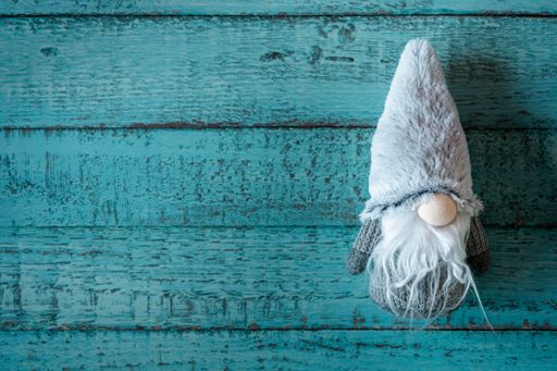 A top view of a cute gray Christmas gnome toy on a blue wooden surface with copy space