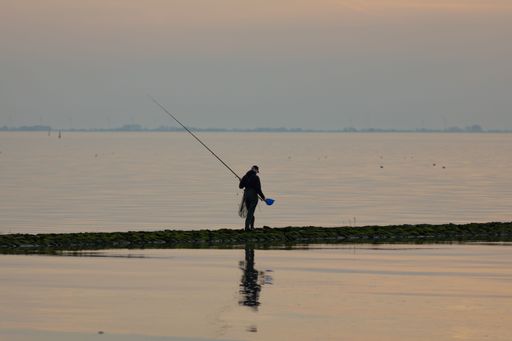 A beautiful shot of a fisherman on the pier during the sunset