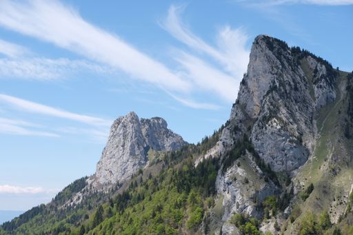The Swiss alps covered with forests and rocks near the French border under a blue cloudy sky
